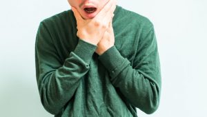 A man holds his jaw after suffering from an injury due to the negligent actions of another aprty