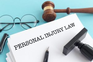 A piece of paper, surrounded by stationery and a gavel, with the words 'personal injury law' written on it in black capital letters.