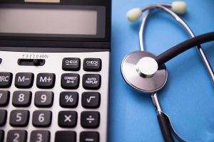 A calculator sitting to the left of a stethoscope, representing a medical negligence compensation calculator.