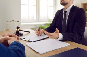 Solicitor at desk discussing compensation for broken thumb with client.