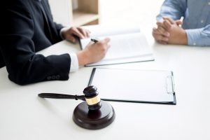 A solicitor and their client discussing compensation for a broken cheekbone with a gavel hammer in the foreground